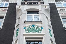 Farbige, florale Stuckornamente am Erker der Straßenfassade.