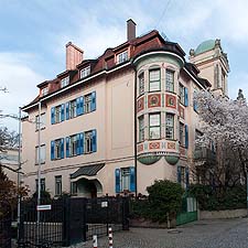 Ansicht von Südwesten: Über-Eck-Ansicht des Wohnhauses Georgenstraße 10. Der Fassadenschmuck spielt zwischen Jugendstil und ländlichen Motiven.