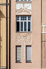 Blick von Süden auf die Fassade des Hauses Am Harras 16: Fassaden ausschnitt mit Stuckornament Baum und Stuckornament Blüten.