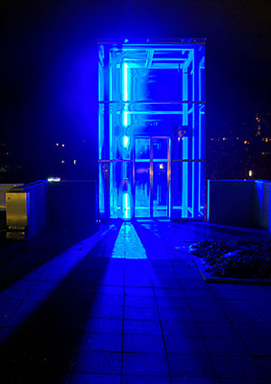 Blau leuchtender Aussenaufzug im
	Eingangsbereich des Klinikums München-Neuperlach