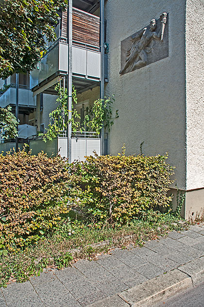 Natursteinplatte mit dem Relief eines Fackeltr�gers an einer Hauswand an der Ofterdingenstraße.