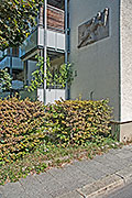 Natursteinplatte mit dem Relief eines Fackelträgers an einer Hauswand an der Ofterdingenstraße.